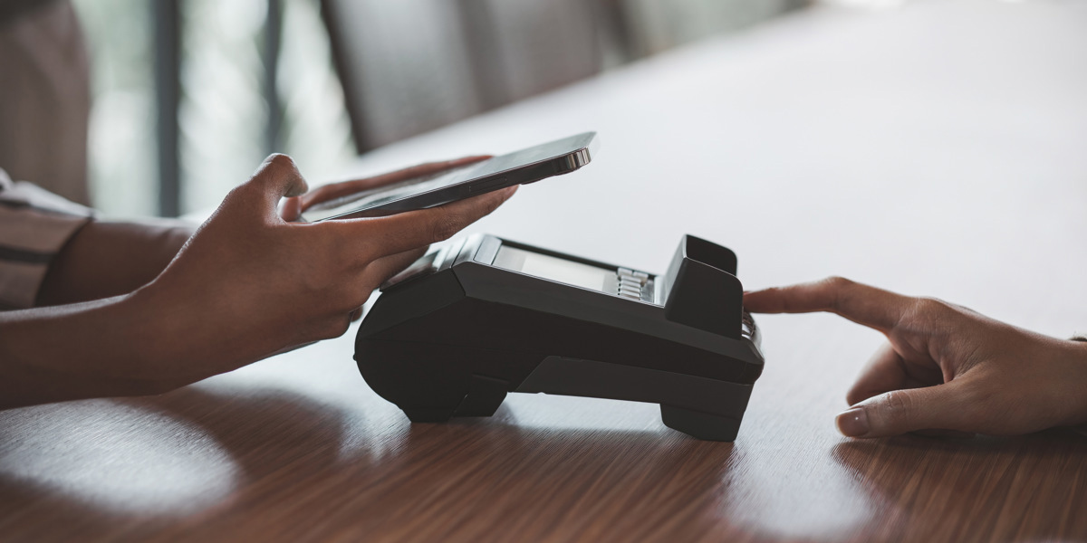 En person som använder en mobiltelefon medan han sitter vid ett bord.