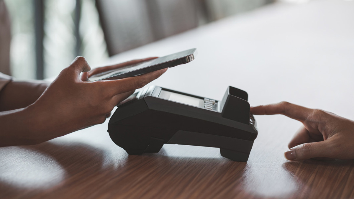 En person som använder en mobiltelefon medan han sitter vid ett bord.