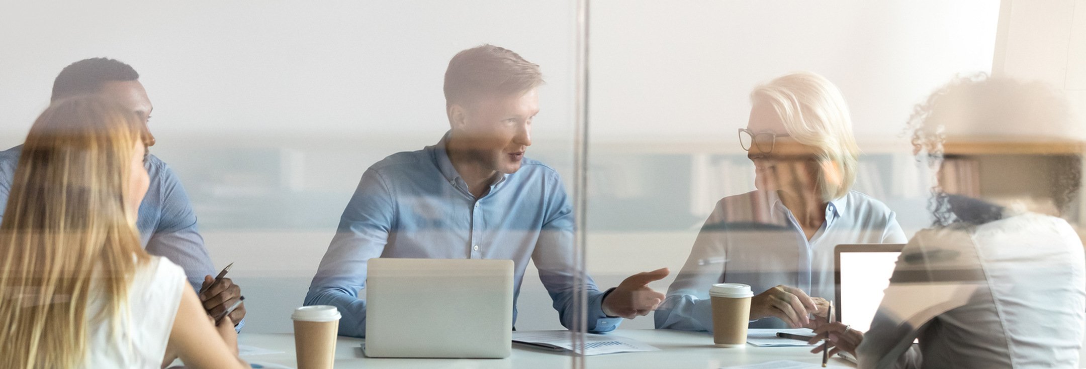 En grupp människor som sitter vid ett bord med bärbara datorer.