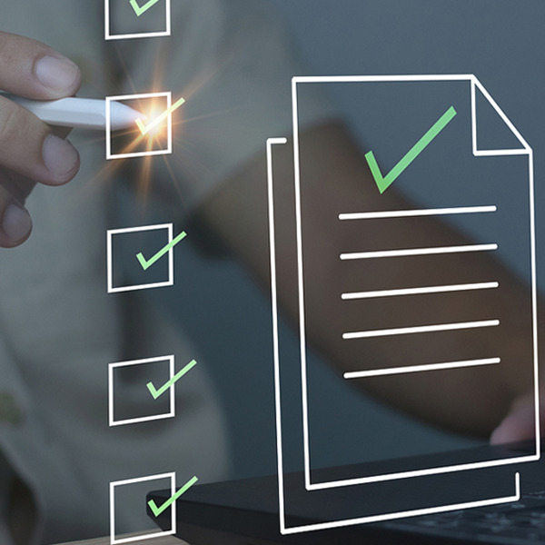 En man arbetar på en bärbar dator med en bockmarkering som kommer ut ur skärmen.