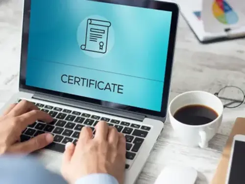 En person som skriver på en bärbar dator med ett certifikat på skärmen.