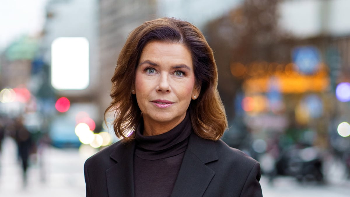 En kvinna i svart kostym står på en trottoar.