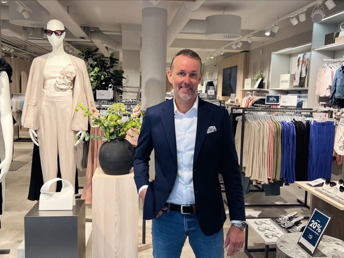 En man står framför en utställning med klänningar.