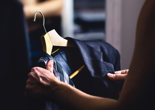 En person försöker knyta en skjorta med en slipsnål.