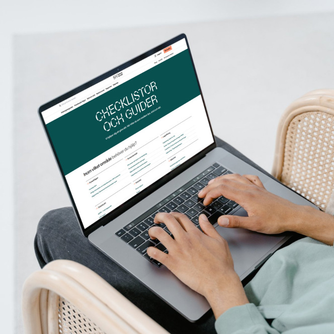 En person som sitter i en stol och använder en bärbar dator.