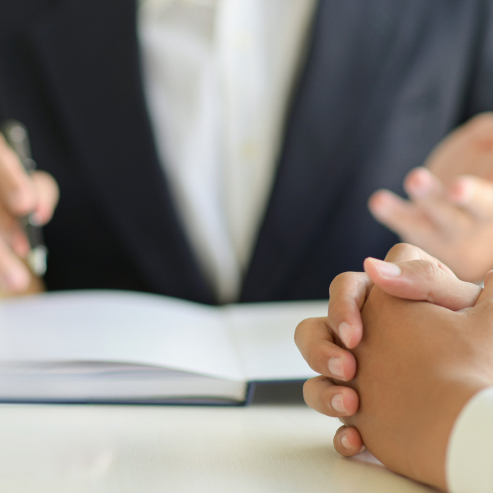 Två personer sitter vid ett bord med en bok och en penna.