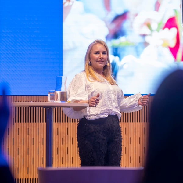 En kvinna står framför en skärm och håller en presentation.