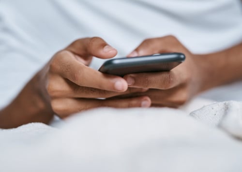 En närbild på en person som håller i en mobiltelefon.