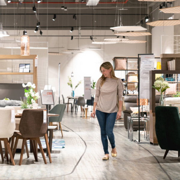 En kvinna som går genom en butik fylld med möbler.