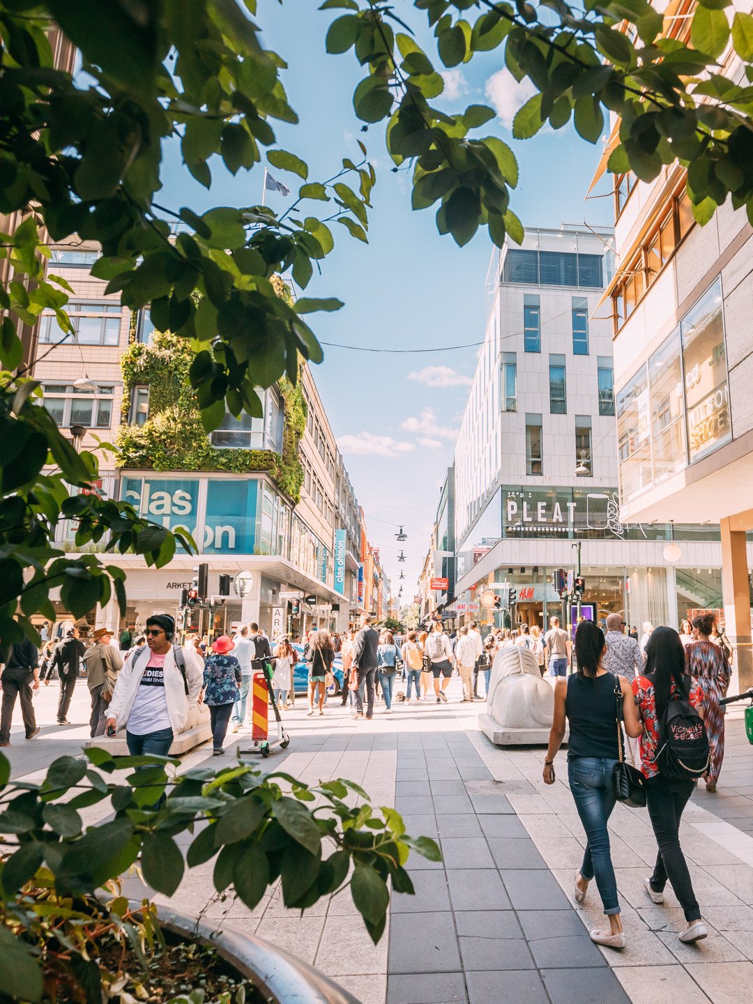 En grupp människor som går längs en gata med butiker i en stad.