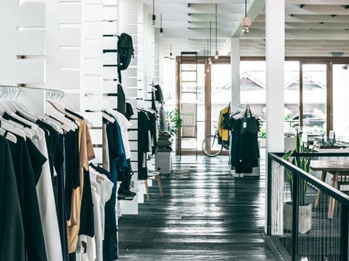 En rad kläder som hänger på en stång i en butik.