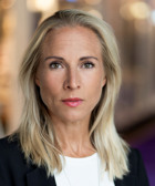 En kvinna med blont hår och svart kavaj.