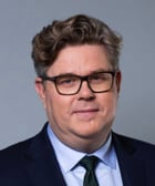 En man i kostym och slips som poserar för ett foto.