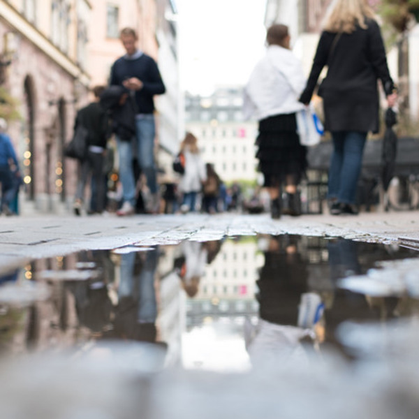 En grupp människor som går längs en gata bredvid en vattenpöl.