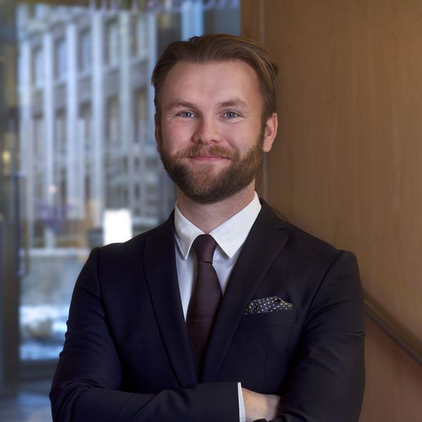 En man i kostym och slips poserar för en bild.