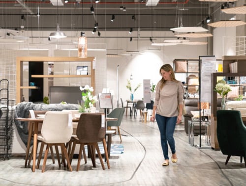 En kvinna som går genom en butik fylld med möbler.