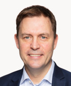 En man i kostym som ler mot kameran.