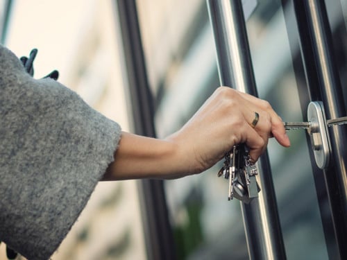 En närbild av en person som öppnar en glasdörr.