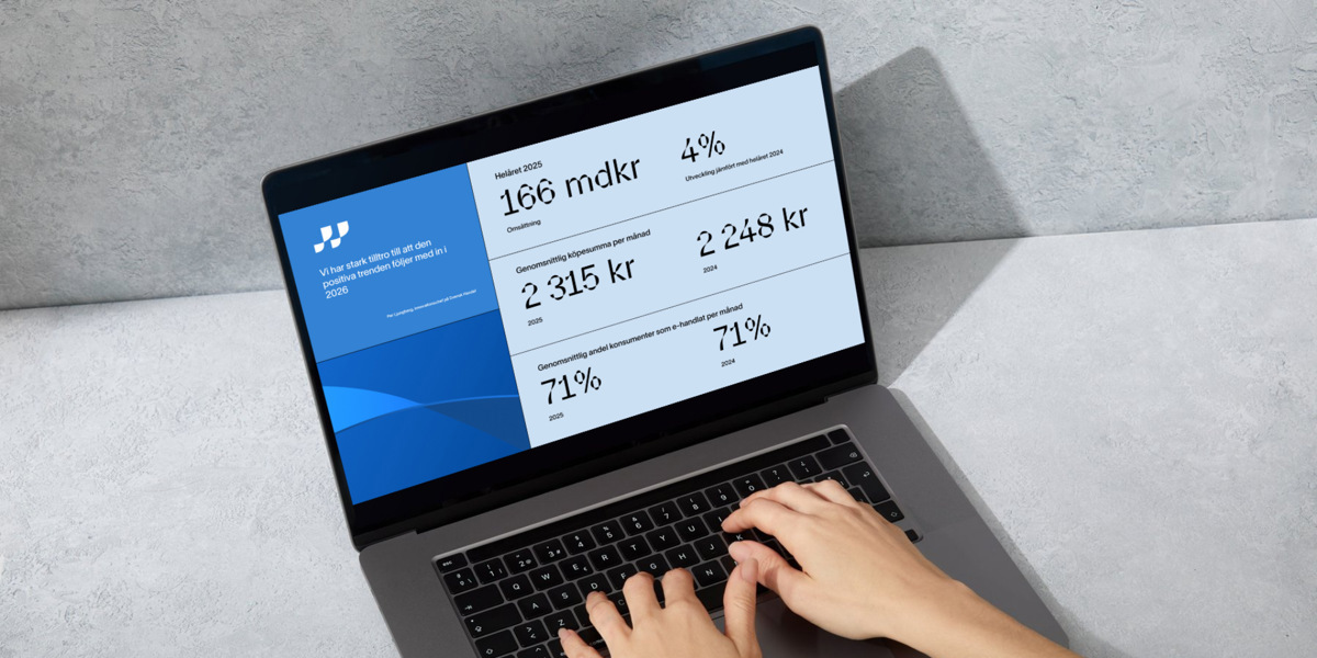 Dator står på ett bord, två händer skriver på tangentbordet och en bild av Svensk Handels rapport E-handelsindikatorn visas på skärmen.
