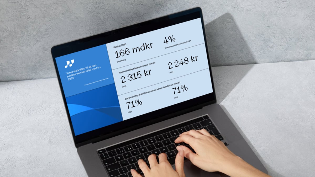 Dator står på ett bord, två händer skriver på tangentbordet och en bild av Svensk Handels rapport E-handelsindikatorn visas på skärmen.