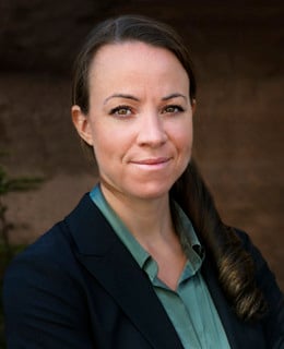 En kvinna i svart kavaj och grön skjorta.