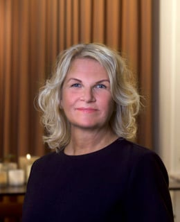 En kvinna i svart topp står i ett vardagsrum.