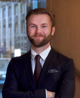 En man i kostym och slips poserar för en bild.