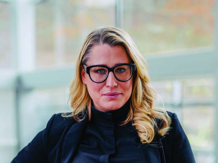 En kvinna står på ett räcke med händerna på höfterna.