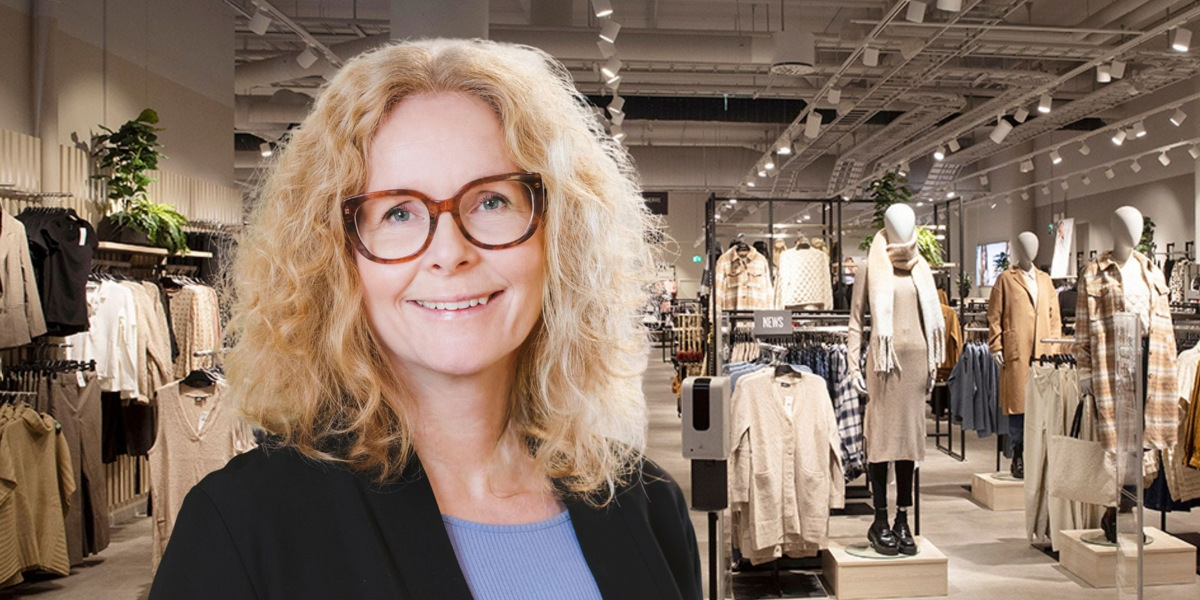 En kvinna som står framför ett klädutställningsställ.