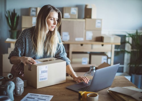 En kvinna sitter vid ett bord med en bärbar dator framför sig.