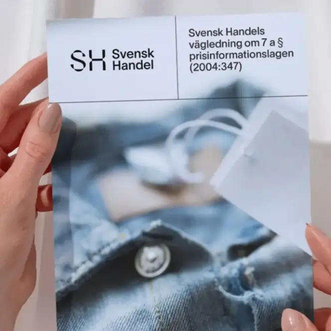En person som håller upp en tidning med en bild av en skjorta på.