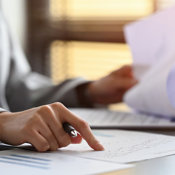 En person som sitter vid ett skrivbord med papper och penna.