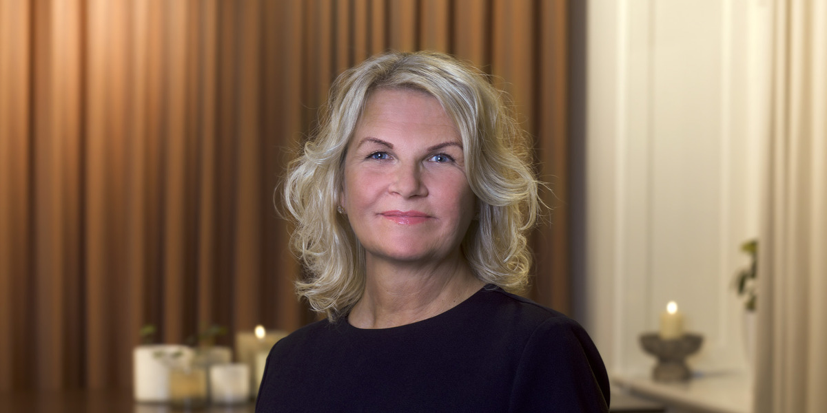 En kvinna i svart topp st&aring;r i ett vardagsrum.