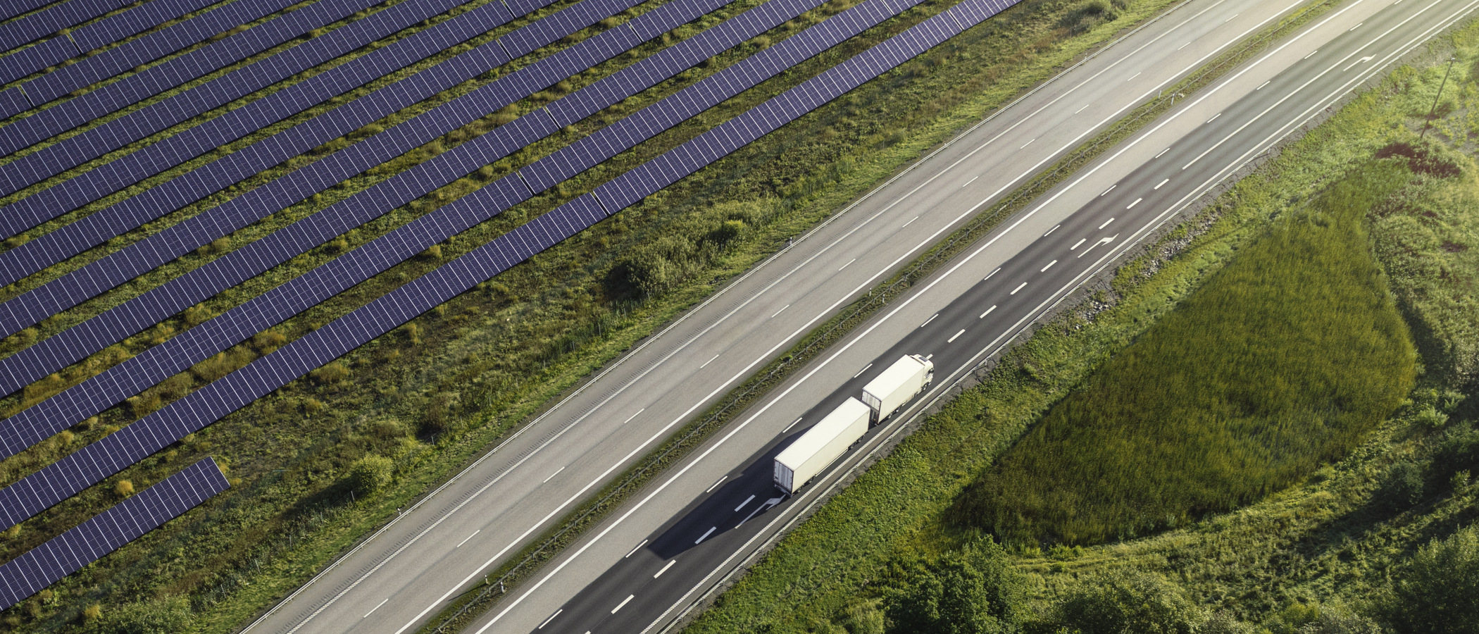 En lastbil som kör på en väg bredvid en skog.