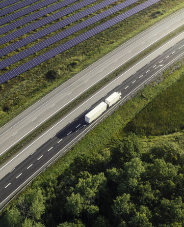 En lastbil som kör på en väg bredvid en skog.