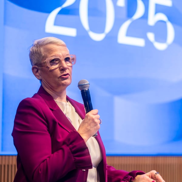 En kvinna talar i en mikrofon inför en folkmassa.