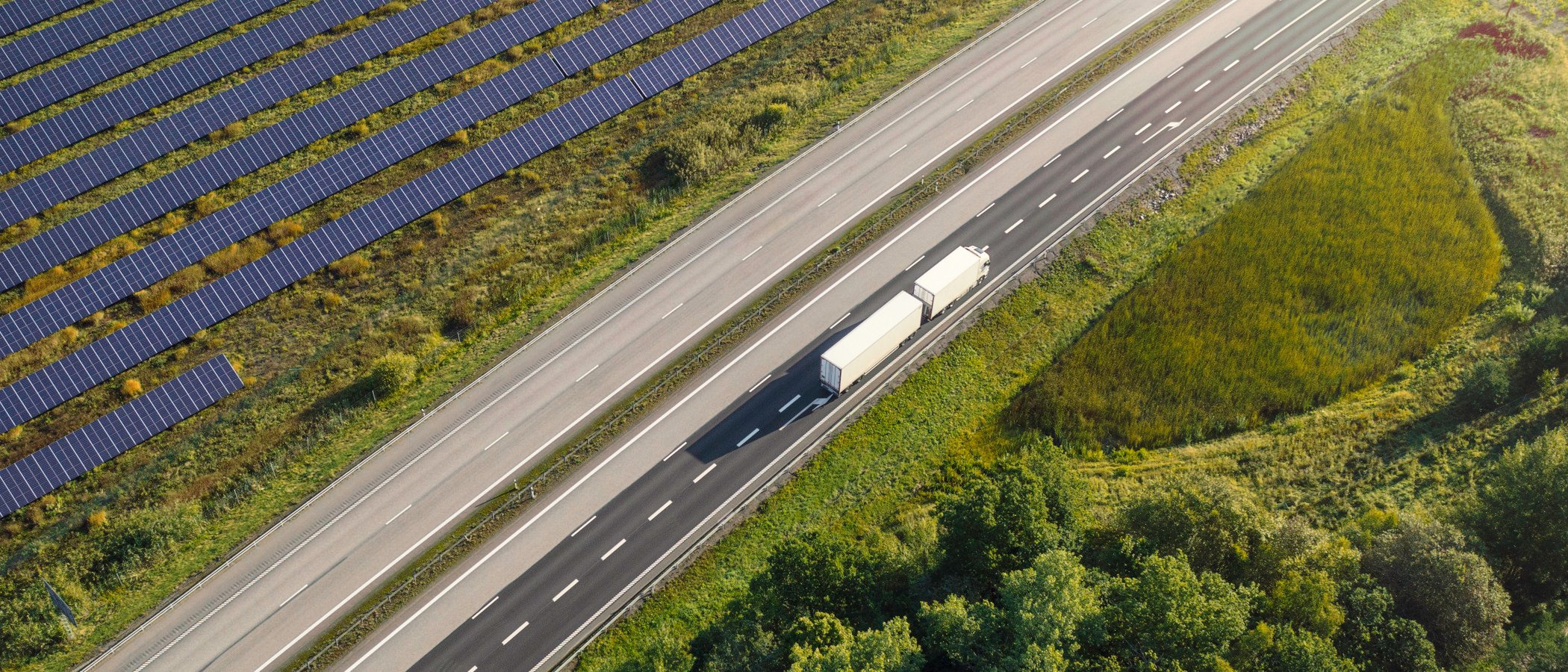 En lastbil som kör på en väg bredvid en skog.