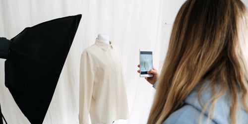 En kvinna tar en bild av en klänning på en skyltdocka.